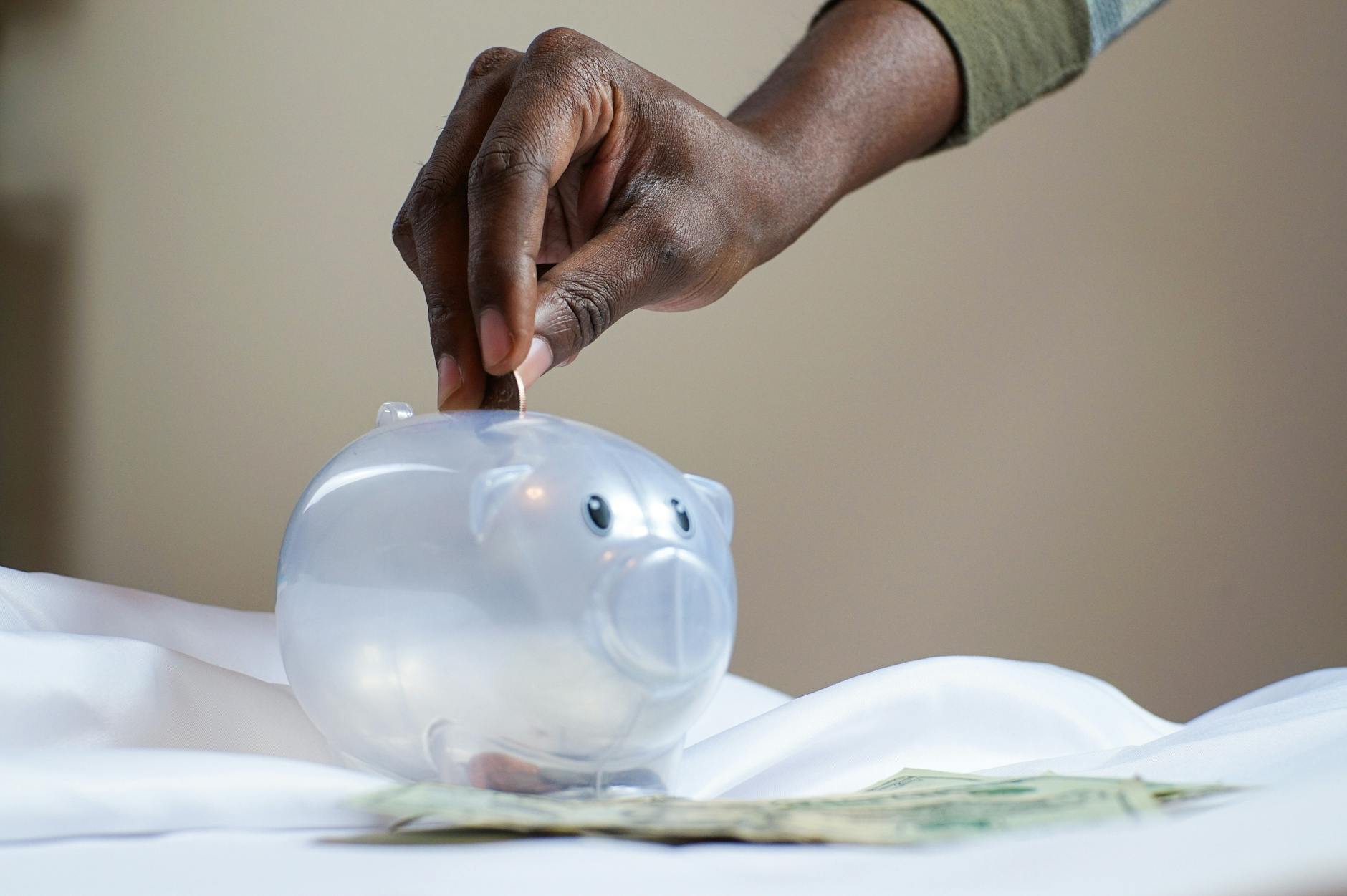 person putting coin in a piggy bank how to drastically cut expenses